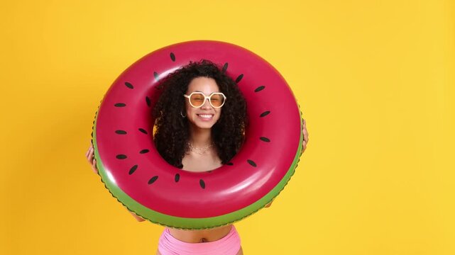 Beautiful woman with inflatable ring wearing pink swimsuit on orange background