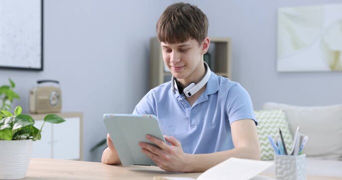 Teenage boy using tablet at wooden table indoors
