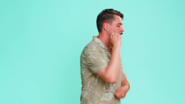 Middle-aged man enthusiastically imitates drumming with hands in the air, showing energy and joy through imaginary play. Young adult guy isolated on blue background expressing musical rhythm and fun.