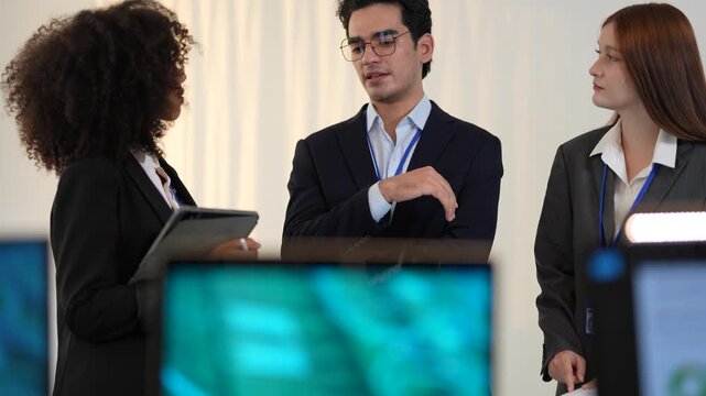 Poised cross functional specialists including african american woman and asian male managing digital safeguard protocols and network security within a state of the art command center.