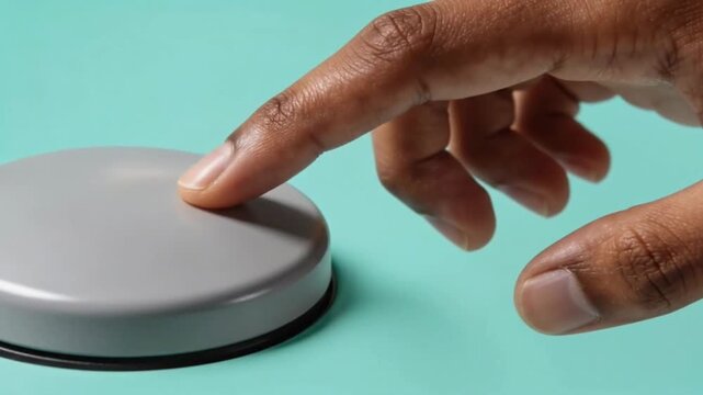 Finger pressing a gray button on a teal surface