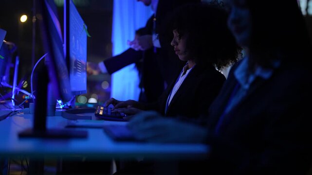 Versatile technical team of professionals showing professional colleagues from varied backgrounds scrutinizing advanced AI and neural network patterns at a high tech operations center at night.