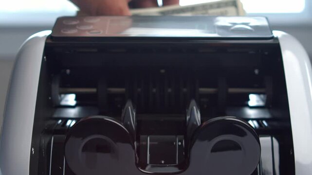 Watch as a sleek money counter machine efficiently processes stacks of cash at an office. Experience the smooth, rhythmic movements of the bills being sorted