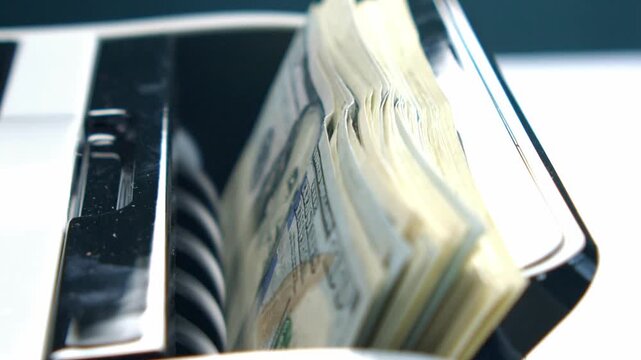 Bank employees efficiently manage stacks of currency as they feed them into a sophisticated counting machine, observing the seamless flow of cash transactions