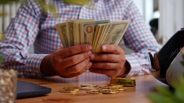 Hands methodically sort through stacks of cash and gold coins, showcasing a mix of anticipation and focus in a well-lit workspace during morning hours