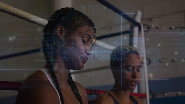 Two women in boxing corner, one wrapping hands for training, other watching HUD tracking tension