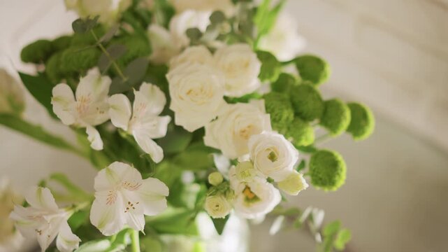 Vivid bouquet of roses and mums brightens home kitchen setting. Charming floral centerpiece featuring pink roses alstroemeria and green button mums in glass vase under gentle morning light