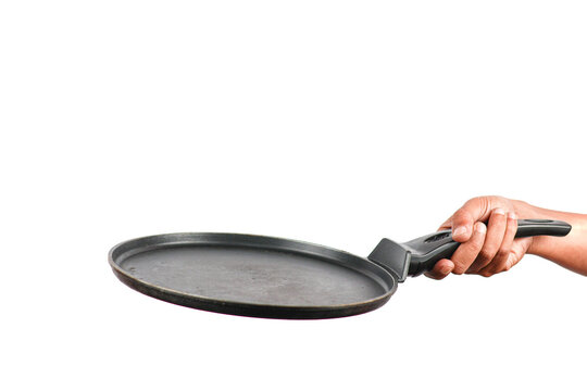 Hand holding a black non-stick crepe pan or flat griddle isolated on white background.