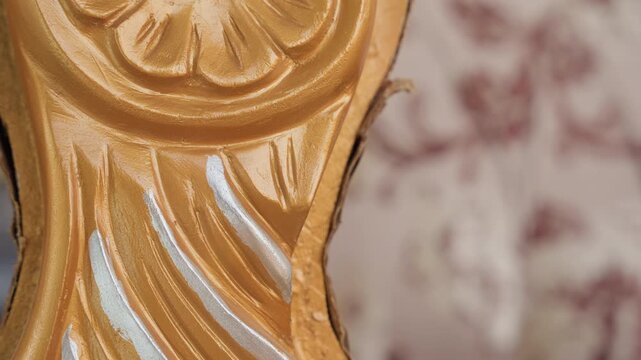 Careful polishing of vintage carved furniture with gold and silver highlights. Restoration process of ornate gilded furniture showcasing intricate floral patterns and metallic accents