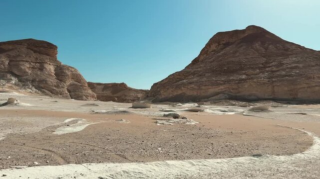 Motion in desert valley with limestone cliffs and eroded sandy ground