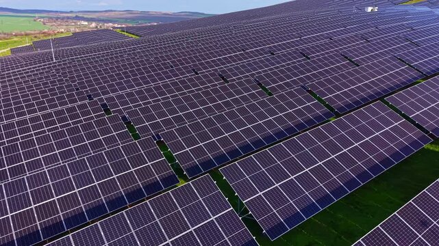 An expansive field of solar panels stretches across the land, soaking up sunlight to generate clean energy. The bright blue sky complements the endless rows of panels.