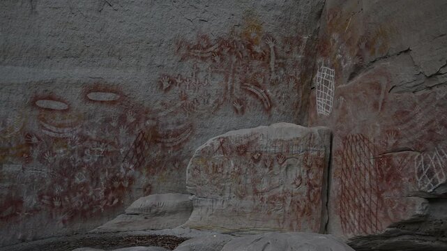 Ancient Aboriginal rock art on sandstone wall in Carnarvon Gorge, Australia, detailed indigenous paintings, cultural heritage site, historic storytelling, natural textures, iconic outback landscape.