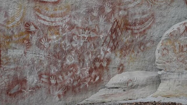 Ancient Aboriginal rock art on sandstone wall in Carnarvon Gorge, Australia, detailed indigenous paintings, cultural heritage site, historic storytelling, natural textures, iconic outback landscape.