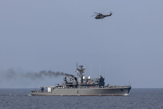 A helicopter flies over a warship during a naval exercise in mediterranean sea.