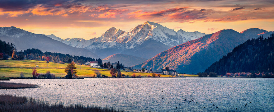 Panoramic morning view of Haidersee (Lago della Muta) lake with Ortler peak on background, Italy, Europe. Exciting autumn sunrise on Italian Alps. Beauty of nature concept background.