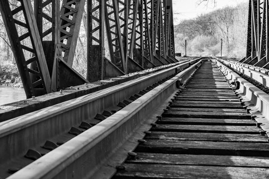 Photo of rusty train tracks.  The image evokes a mood of serene abandonment, with the rusty, sunlit tracks leading the eye towards an uncertain, yet inviting, future. 