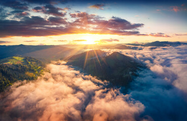 Naklejka premium Stunning sunrise on Carpathian mountains. Fog spreads on the valley of Snidavka village, Ukraine, Europe. Wonderful landscape of mountain hills. Beauty of nature concept background.