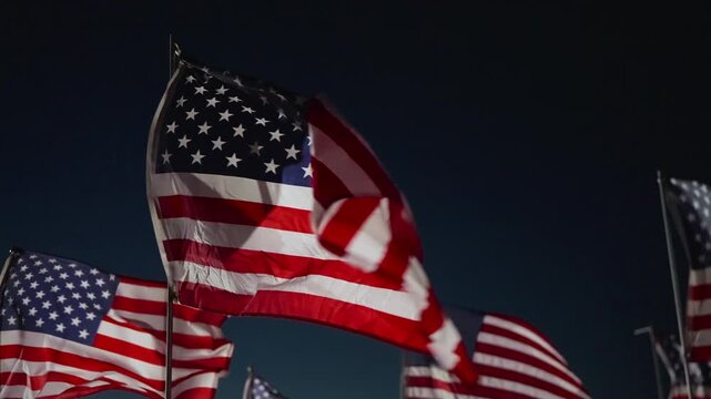 American flag waving close up at night in Malibu, California, USA illuminated by strong lights creating dramatic patriotic tribute and remembrance atmosphere