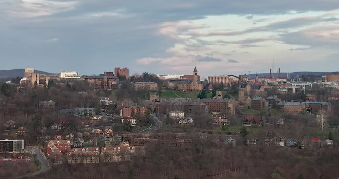 Stunning timelapse video captures a vibrant university campus, where historic architecture meets lush, rolling hills. The dense, emerald canopy of trees frames the scene, all under a dynamic sky. 