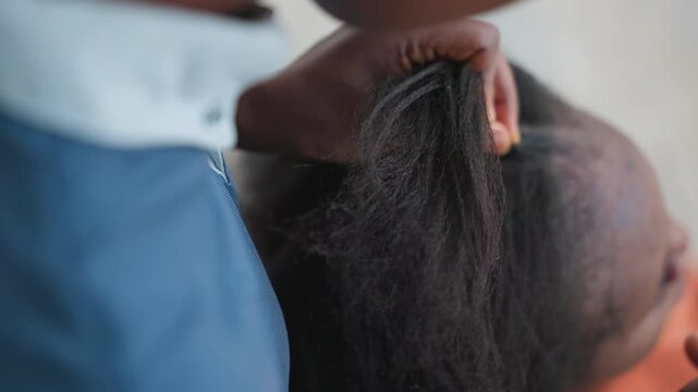 Black stylist braiding hair into cornrows with firm hands and precise parting, closeup scalp work, finished sleek texture, client calm and proud, skillful technique and cultural styling, polished