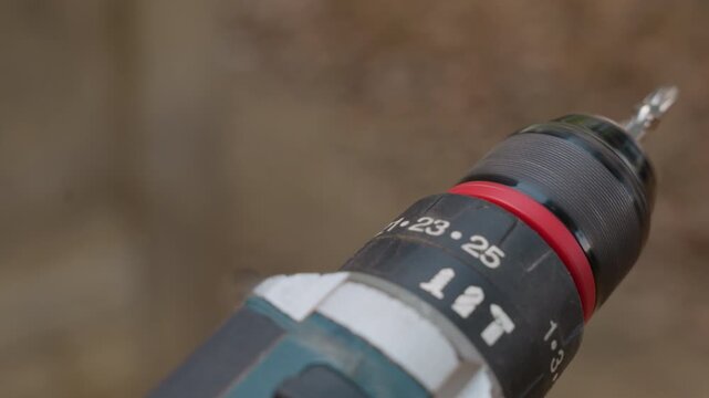 Drill setup completed. Contractor carefully arranges drill for accurate deck construction task. Visual details captured showing outdoor scene with carpenter aligning drill for decking project