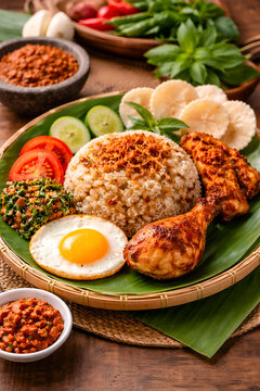 traditional Indonesian Nasi Liwet meal, presented on a round, woven bamboo tray lined with a large, fresh green banana leaf