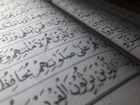 Close up of Arabic letters in an Iqro book for learning Quran with dramatic side lighting.