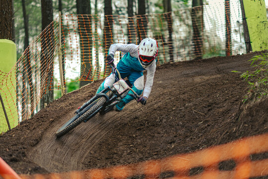 Mountain Biker Racing Downhill Through a High-Speed Berm on Dirt Track