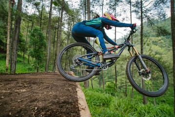 Fototapeta premium Mountain bike rider performing a jump drop on a forest trail