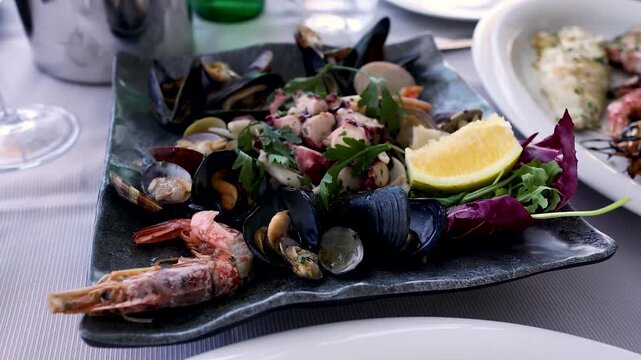 Fresh seafood appetizer platter with mussels octopus and shrimp served at outdoor mediterranean restaurant table.