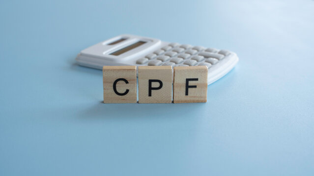 CPF letters on wooden tiles with a white calculator on a blue background for pension fund and retirement savings contribution concepts.
