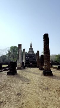 Vertical POV walking towards the ancient laterite stupa and pillars at Wat Chang Lom.