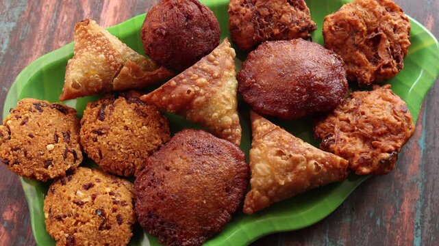 Assorted Kerala snacks Ulli vada spicy onion fritters  Parippu Vada or Paruppu Vadai made with toor dal Samosa crunchy triangular shaped wraps Neyyappam bonda and milk tea undampori. 