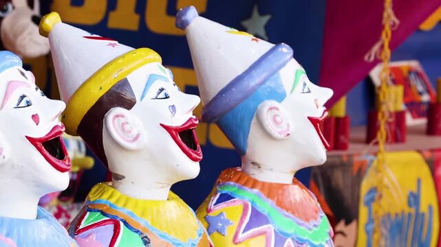 Laughing clown game heads at traditional carnival fairground attraction spinning in motion.