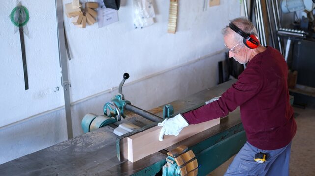 Senior man working wood with jointer machine
