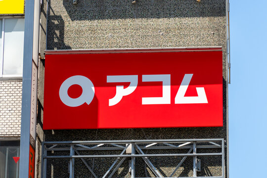 TOSHIMA, TOKYO, JAPAN - APRIL 3, 2026: The official red and yellow branding sign of Acom, a major Japanese consumer finance company, in Toshima, Tokyo.