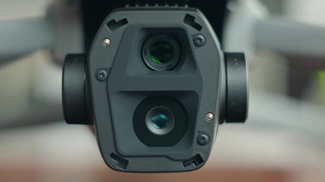 Close-up of drone camera with gimbal stabilizer showing tilt movement mechanism, modern aerial filming technology detail with focus on lens and stabilization system