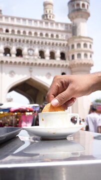 Osmania Biscuit Being Dipped in Irani Chai with Charminar in Background &ndash; Classic Hyderabad Snack