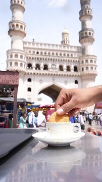 Osmania Biscuit Being Dipped in Irani Chai with Charminar in Background &ndash; Classic Hyderabad Snack