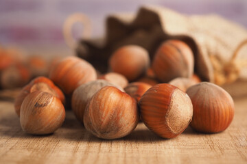 Obraz premium Hazelnuts on a wooden table with a cloth bag nearby