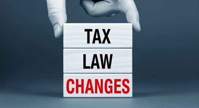 Hand holding stacked wooden blocks with 'Tax Law Changes' text, symbolizing legal and financial adjustments