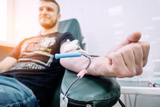 A man sits in a medical clinic donating blood, showcasing the donation process and healthcare environment. The mood is calm and supportive.