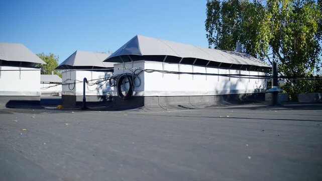 Sturdy well-maintained roof features multiple overhead cables. Gently angled roof with dark shingles crossed by visible electrical lines