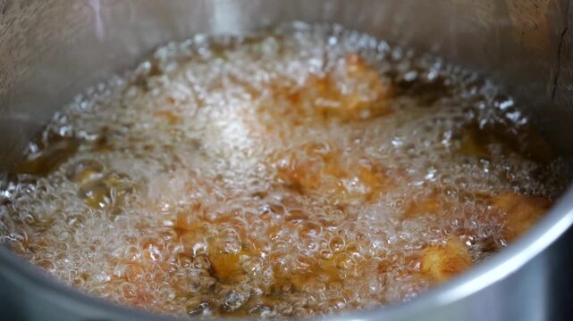 Sizzling sound of squid tempura being deep fried in a stainless steel pot