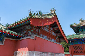Fototapeta premium The image captures the intricate green glazed tiles, traditional roof ornaments, and vibrant red walls of a historic building within the Temple of Heaven complex in Beijing, China 28 May 2025