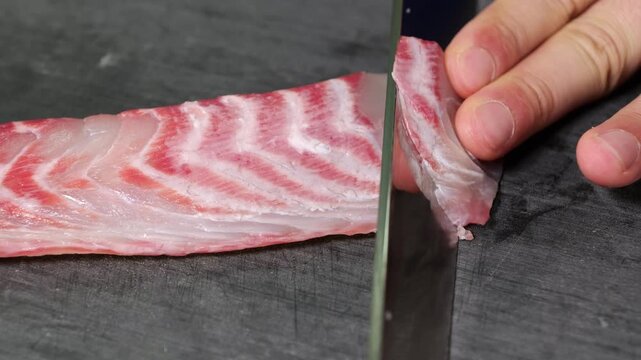 Close-up of a chef slicing fresh raw fish with a professional sashimi knife