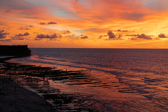 Aerial view of Balangan Beach curved shoreline with reef at sunset