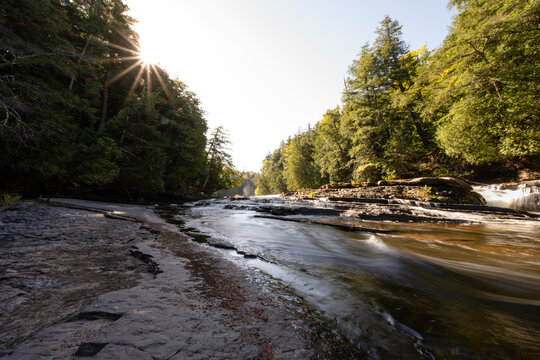 River flowing over rocks with sun flare in Michigan forest