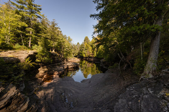 River flowing through narrow rock gorge with forest reflection