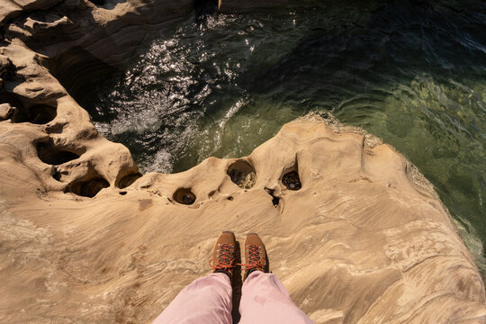 Person's feet wearing hiking boots and pink pants on sandstone rock